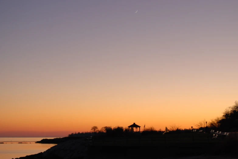 a view of a sunset on the horizon with the light house in the distance