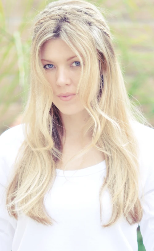 a woman with blonde hair and blue eyes wearing a white shirt