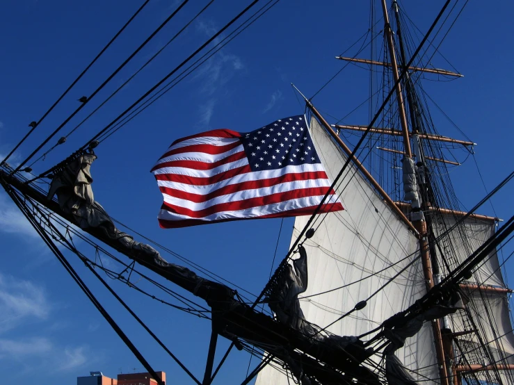 a flag on top of a ship next to wires