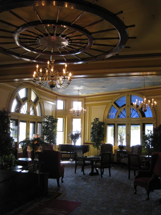 a room with windows, chandeliers and chairs