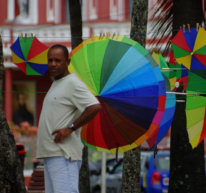 a man holding several colorful umbrellas behind him