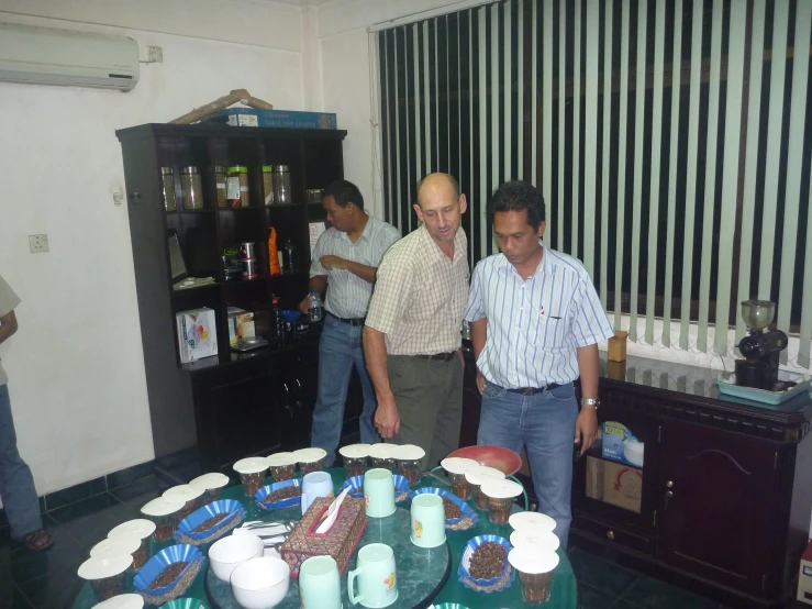 four men are standing around the table that has cake on it