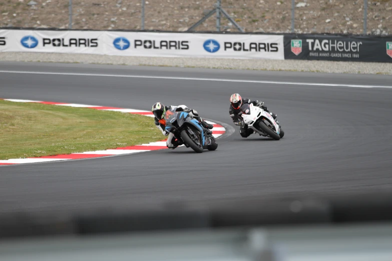 two men riding motorcycles around a race track