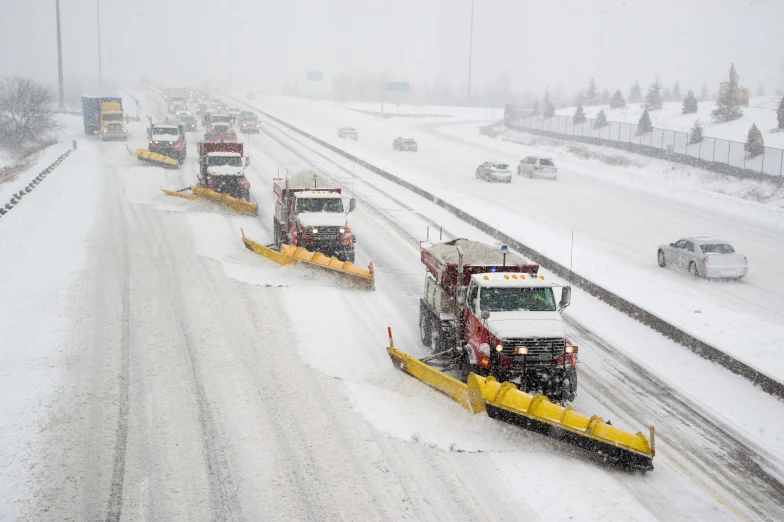 a line of snow plows along an icy highway