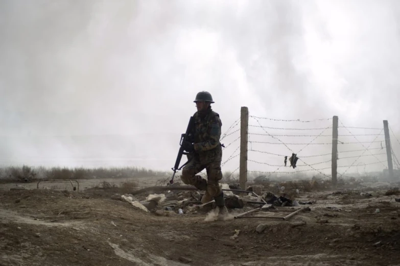 the soldier is walking around near a barbed wire fence