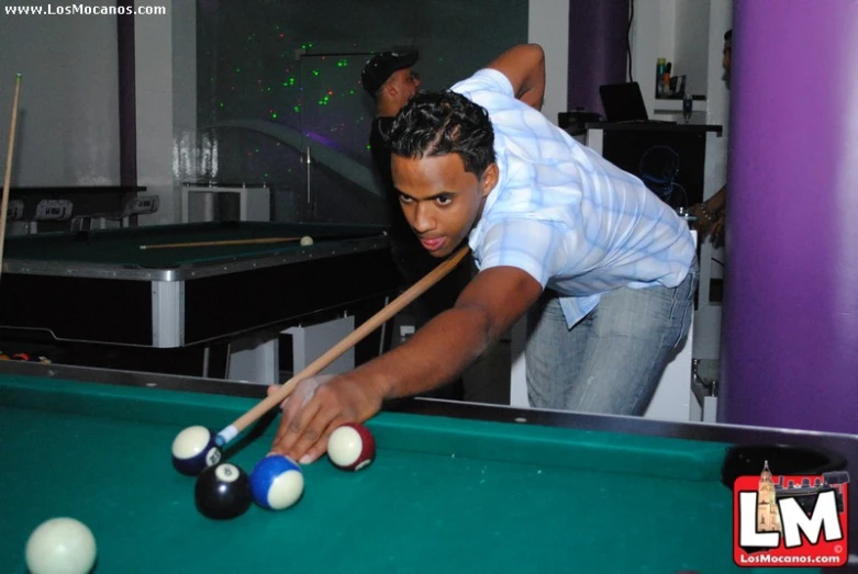 a man leaning over a pool table to hit a ball