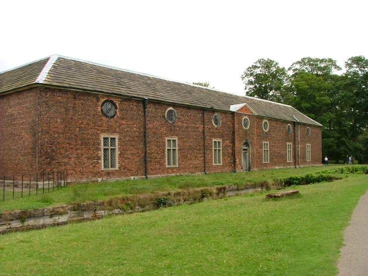 an old brick building with a green yard