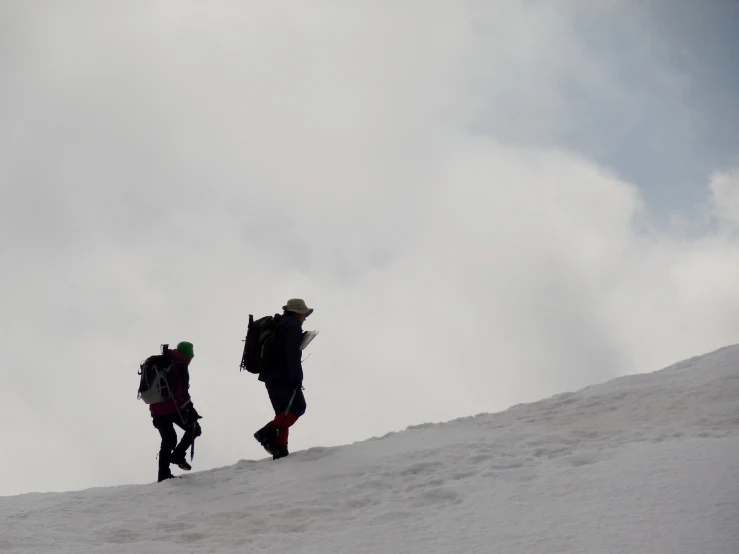 two people hiking up a snowy hill