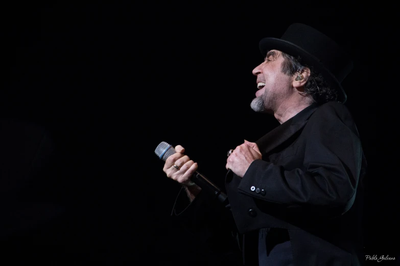 a man with a microphone on stage in the dark