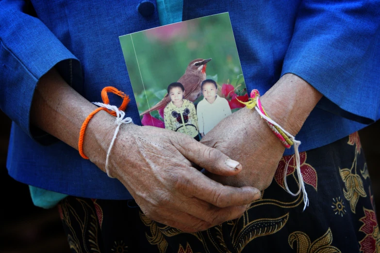 person in blue shirt holding an card with an image on it