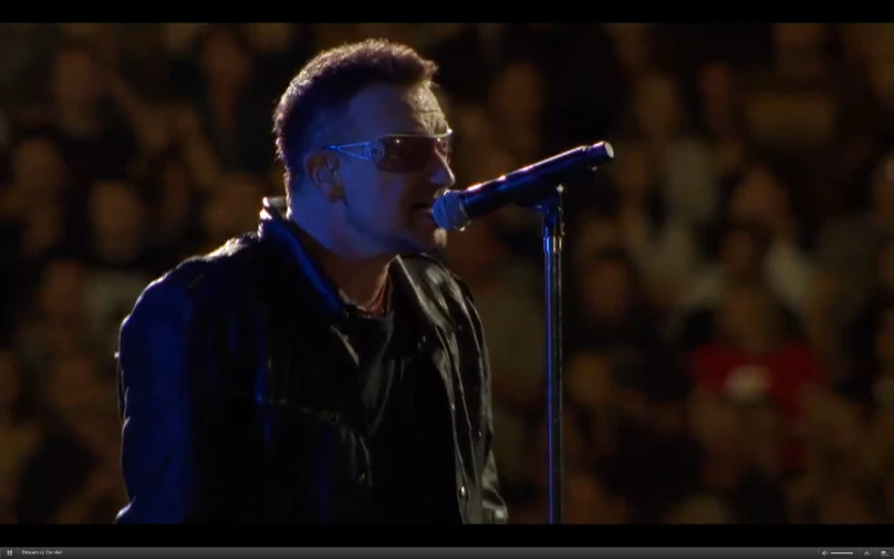 a man wearing shades standing in front of a microphone