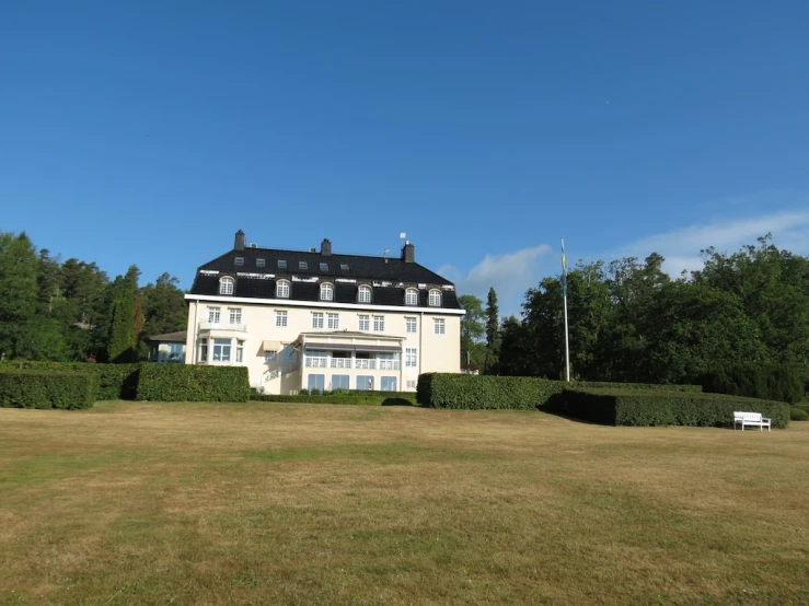 a big white house next to an evergreen filled hill