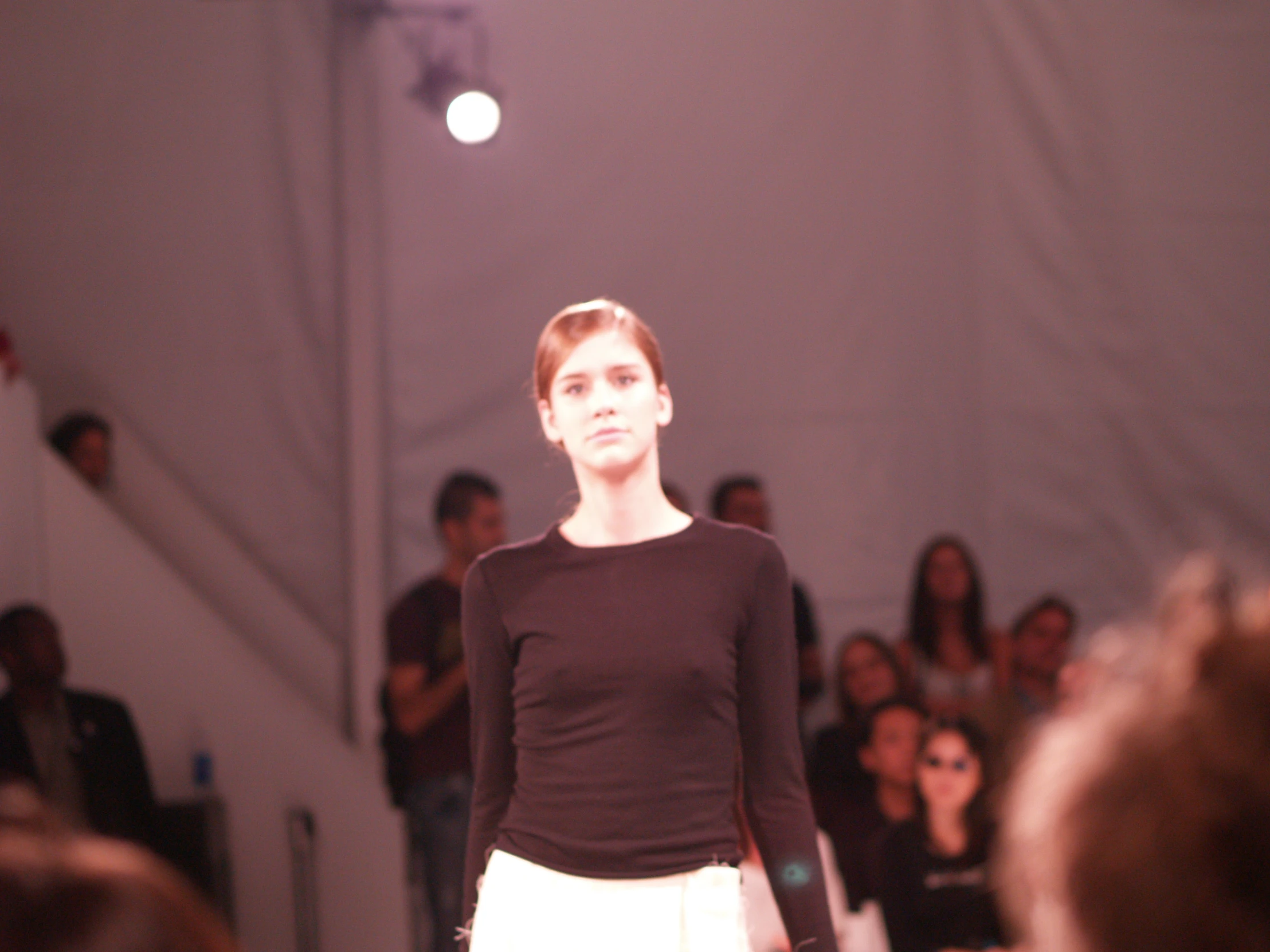 a female model walks down the runway with other models