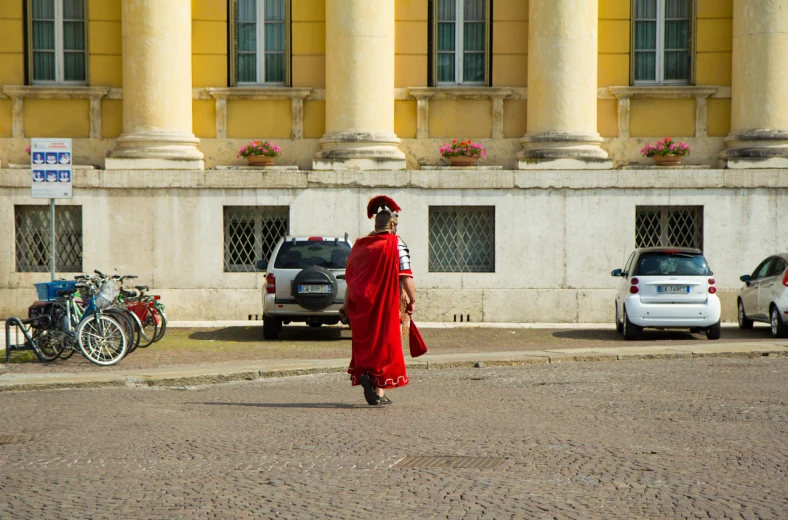 a person with a red outfit is walking in front of some cars
