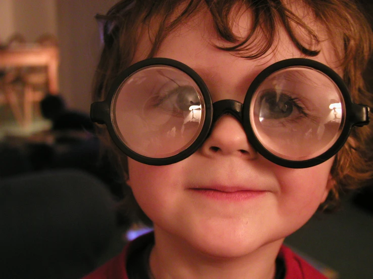 a child wearing big glasses looking at the camera