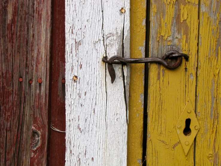 there is an open rusted lock on a yellow door