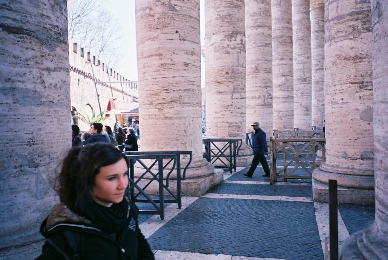 the woman is walking around a bunch of pillars