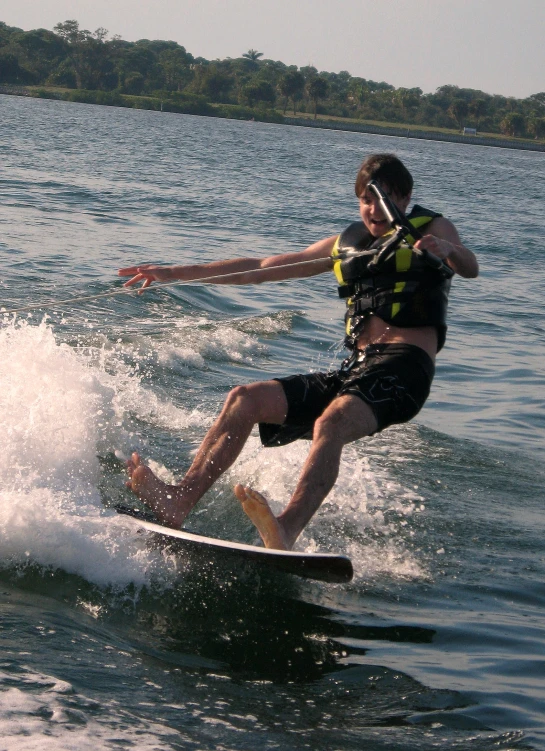 man surfing on water near shoreline of lake