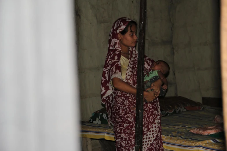 a woman in colorful clothing holds a baby