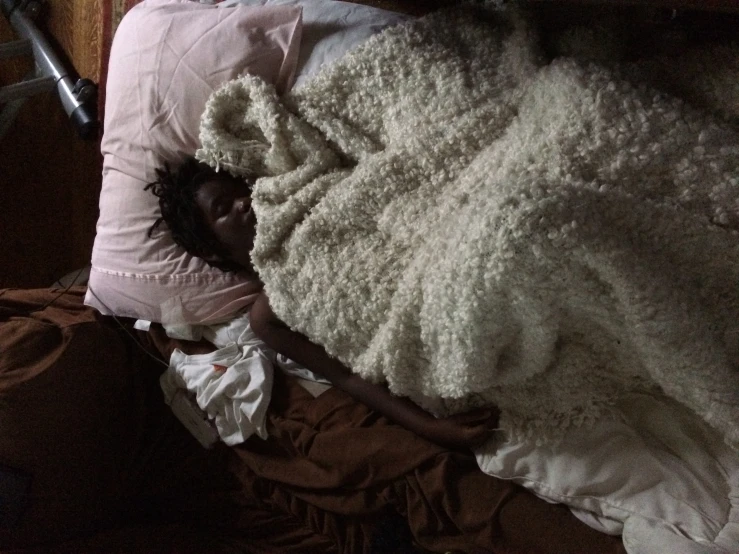 a person sleeping on a bed with a blanket
