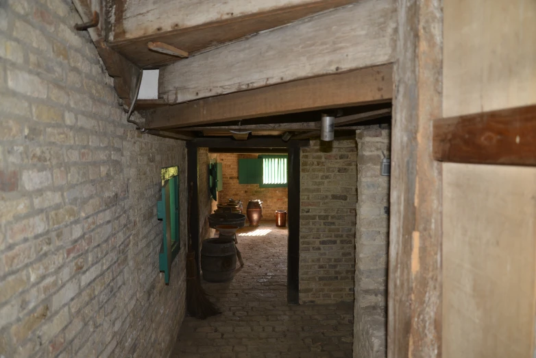 a narrow hallway with brick walls and a barrel next to it