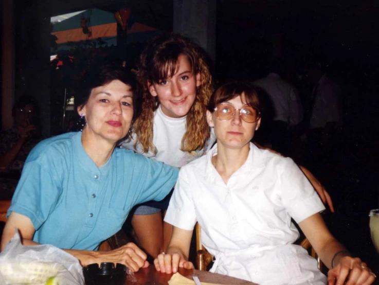 a picture of two women sitting next to a girl on a table