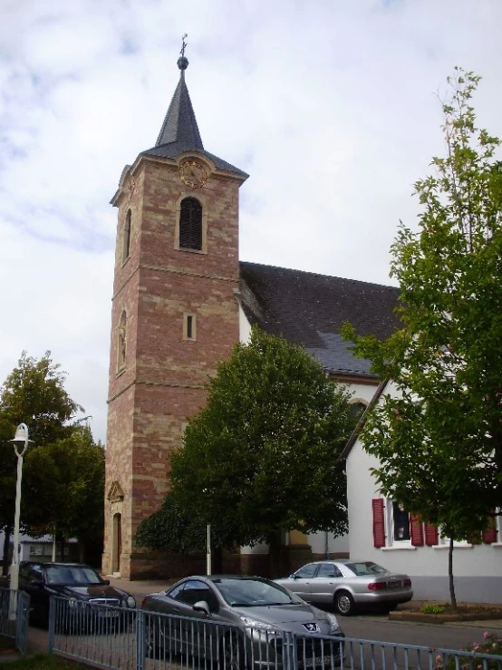 a church with a tower that is sitting above parked cars