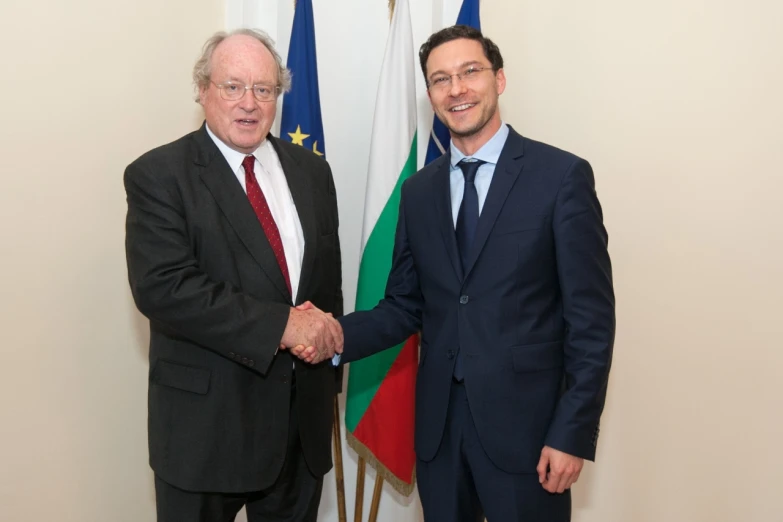 two men standing next to each other shaking hands