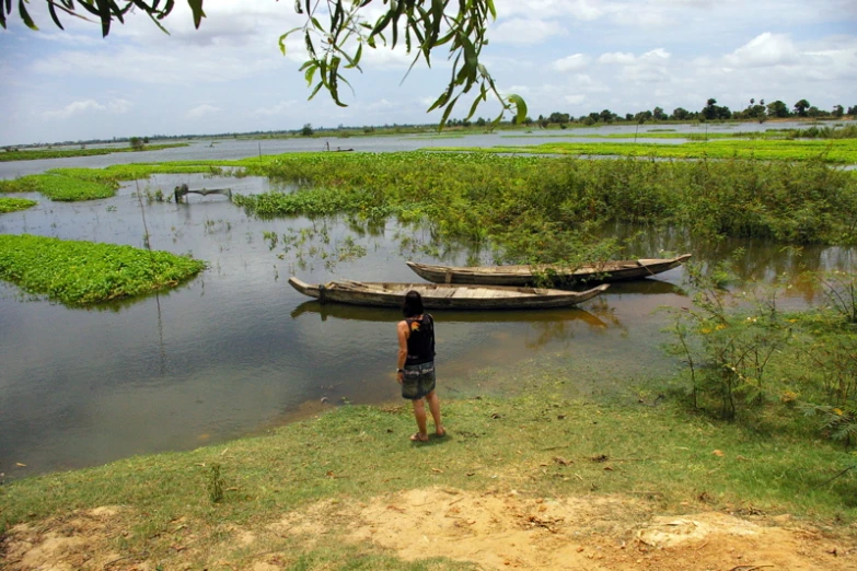 a man in a black shirt standing next to two small boats