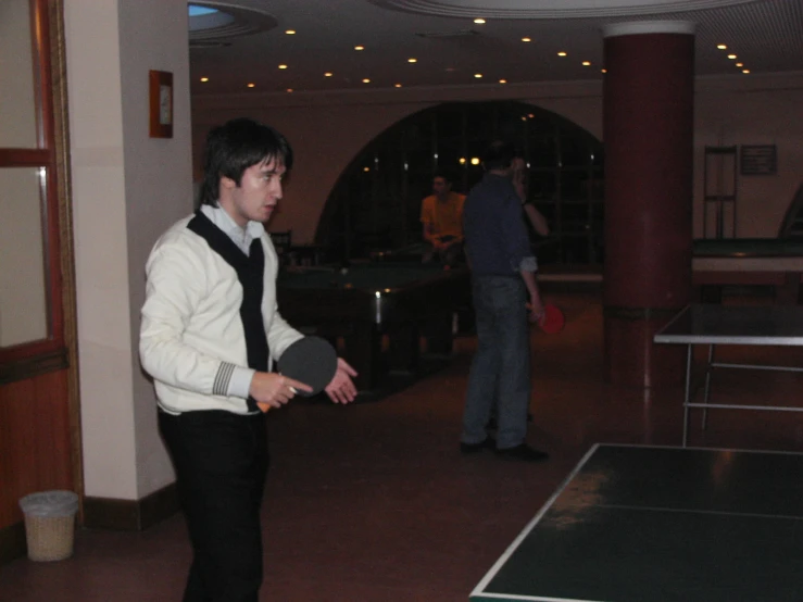 young man playing ping pong in large indoor event venue