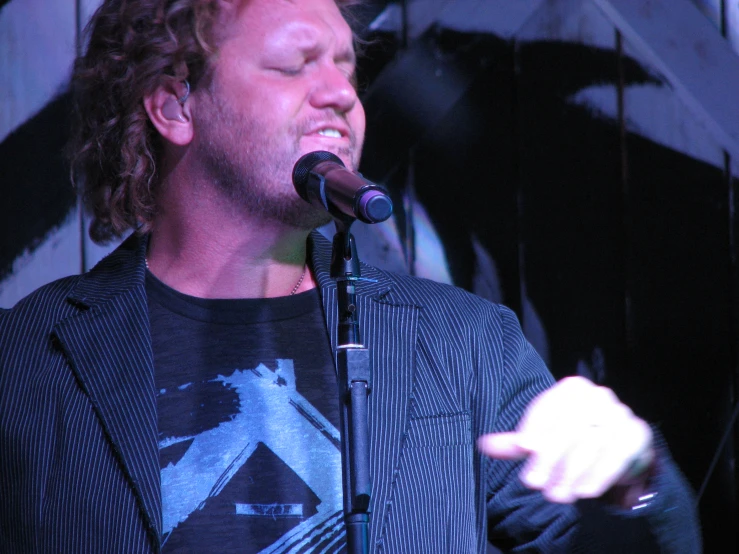 a male singer in a black shirt and a microphone