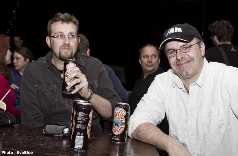 two men are drinking beer while sitting at a table