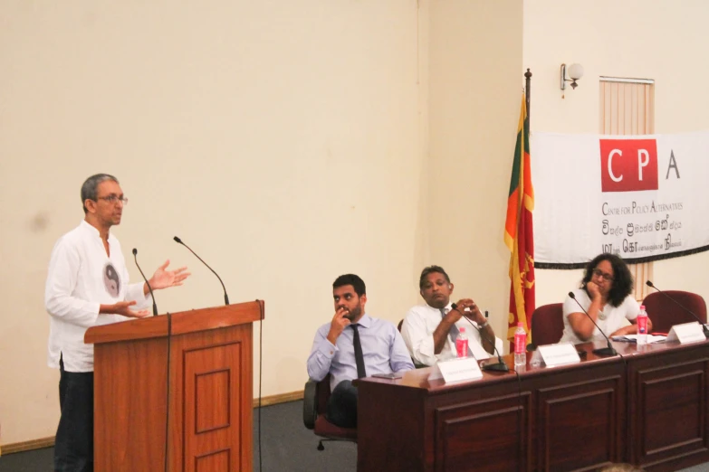 several people sitting around a wooden podium while talking