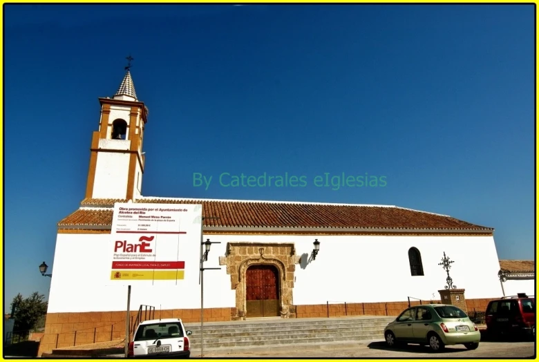 a white church with a tall tower next to parked cars