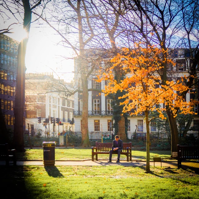 two people sitting on wooden benches in the sun