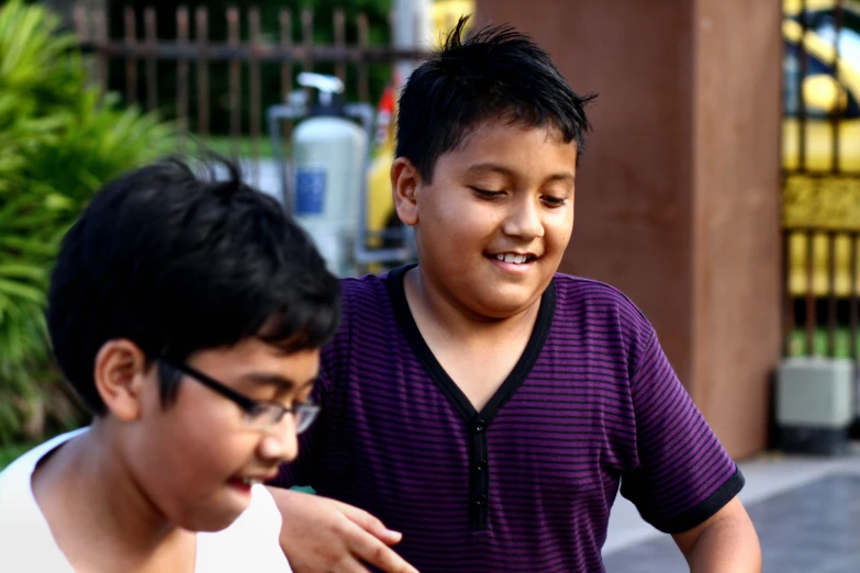 a young man showing another  soing on a cell phone