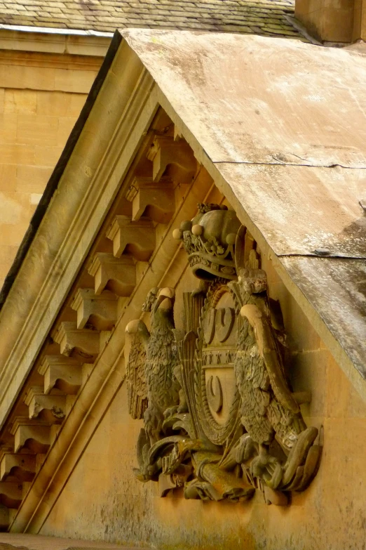 the design on the front of a building shows a coat of arms and birds