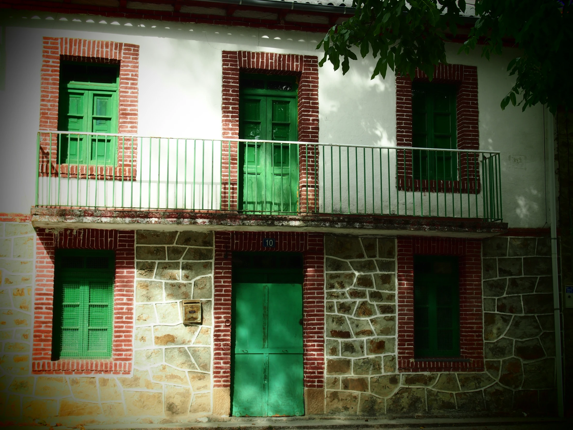 an old house has two green shutters on one floor and three windows and one in the other