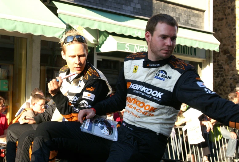 two men are in racing suits sitting on a motorcycle