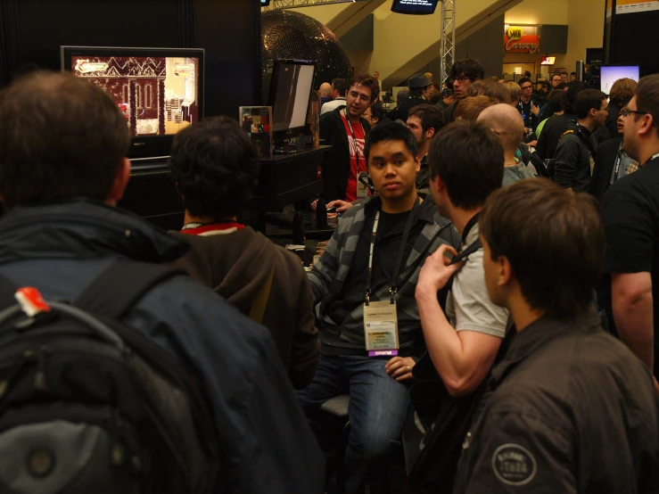 people stand together in a crowded room next to a tv