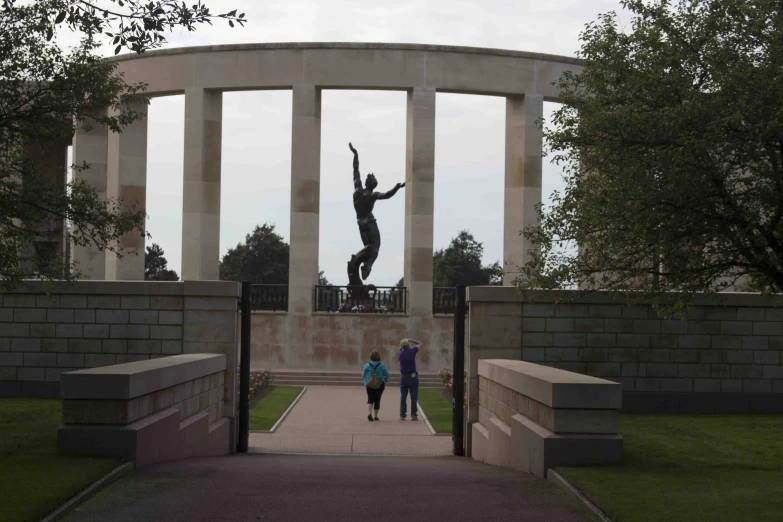 two people walking through a gated entrance to a statue