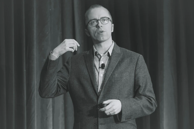 a man in glasses is standing with his arm up