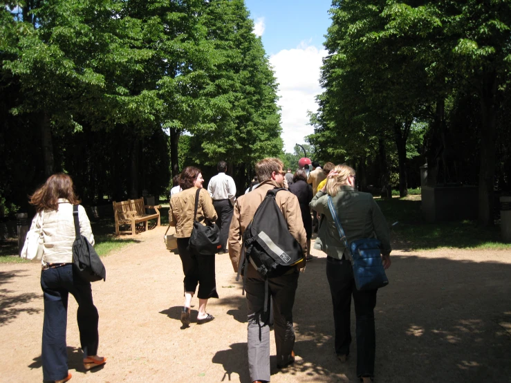 a group of people walking along a path by trees
