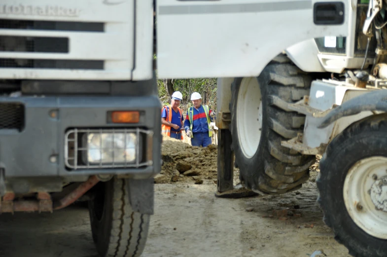 the two workers are standing near a big truck