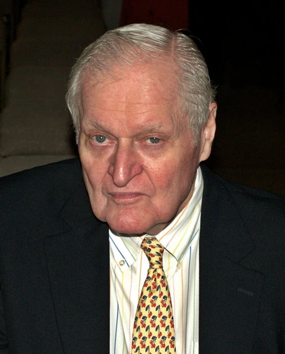 an older man wearing a suit and tie looking at the camera