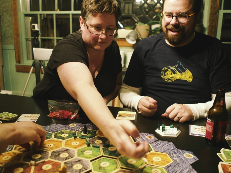 two people at a table holding up a card game