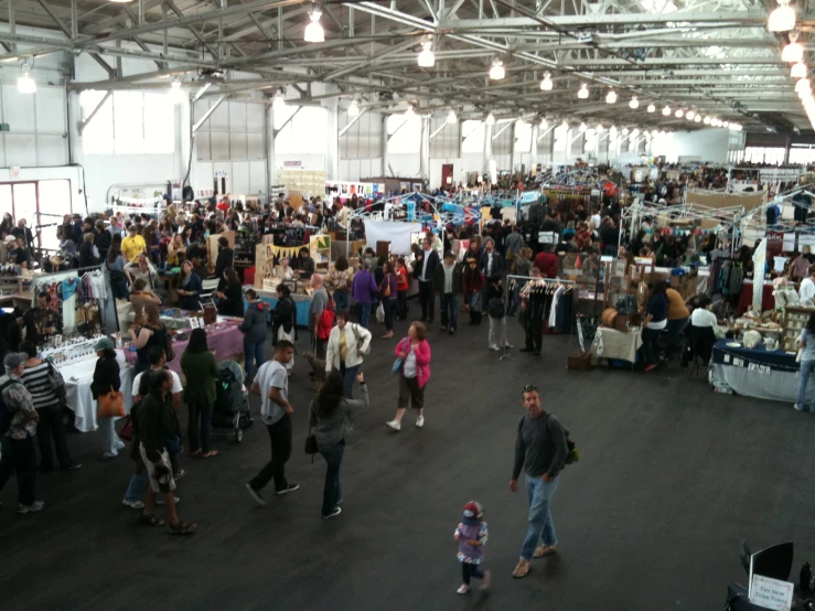 many people standing around talking and walking in a large open building