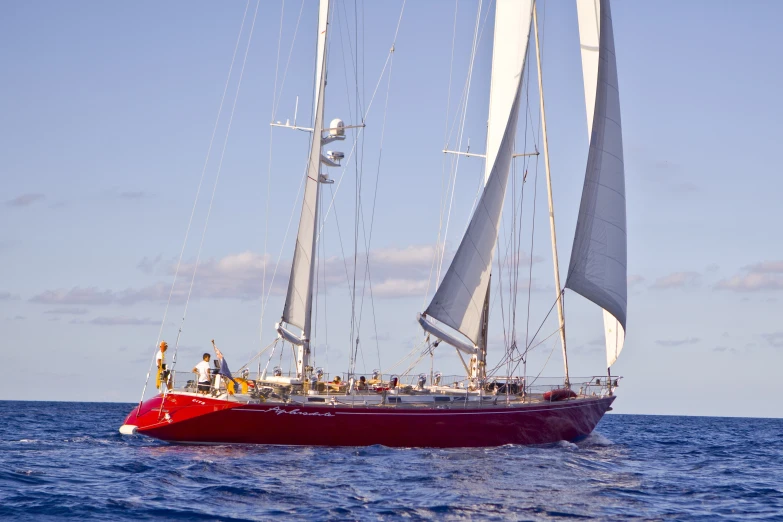 a red sail boat floating in the blue water