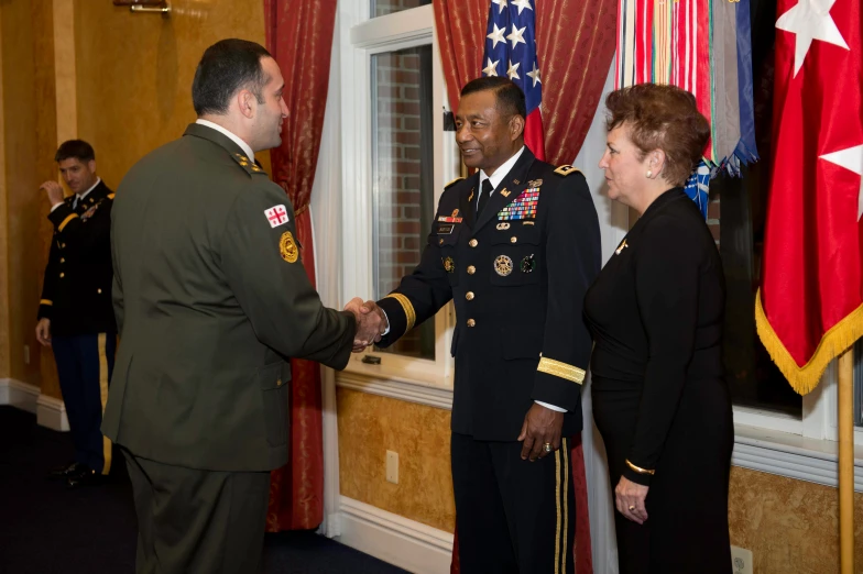 two men shaking hands near flags and a woman