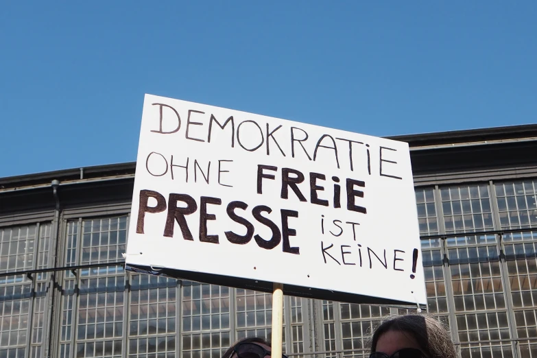 two woman holding protest signs with building in background